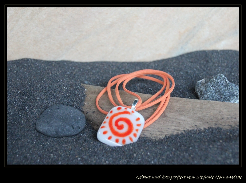 Weißer Fusingglas Anhänger mit orangefarbener Spirale an Velourband